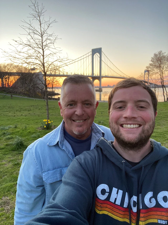 Michael and his father standing in front of a bridge at sunset