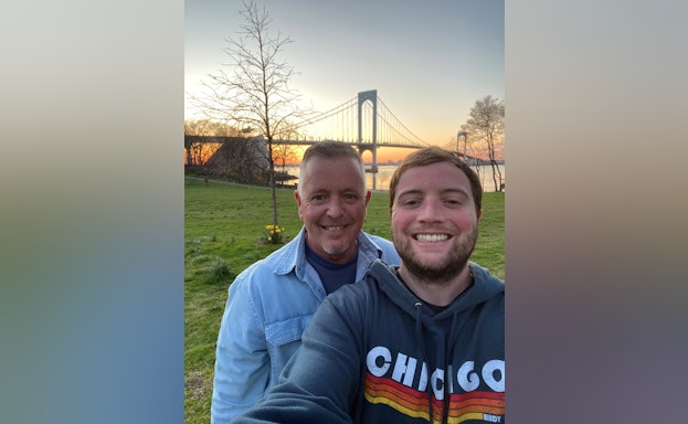 Michael and his father standing in front of a bridge at sunset