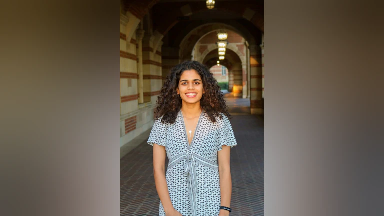 Meera Varma smiling at the camera in front of an archway