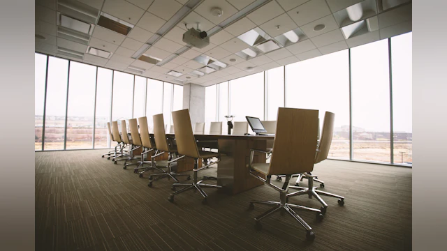 Photo of a an empty conference room with a long table and chairs .