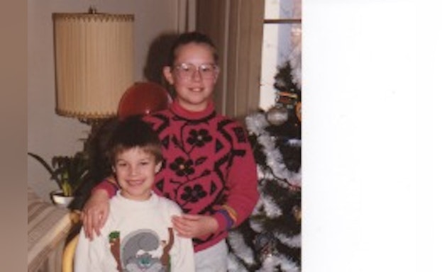 Two children smiling next to a Christmas tree.
