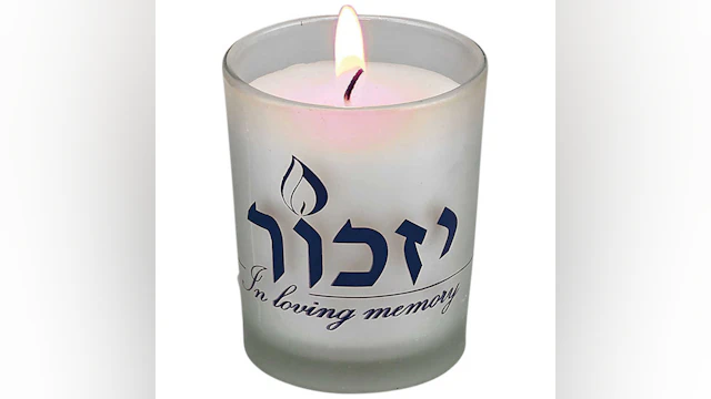 Lit yahrzeit candle that says "In loving memory"