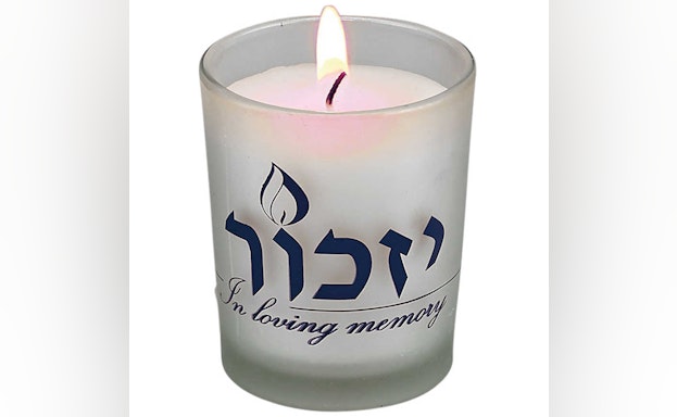 Lit yahrzeit candle that says "In loving memory"