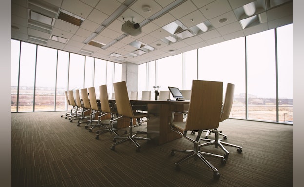 Empty office room with a long table surrounded by rolling chairs