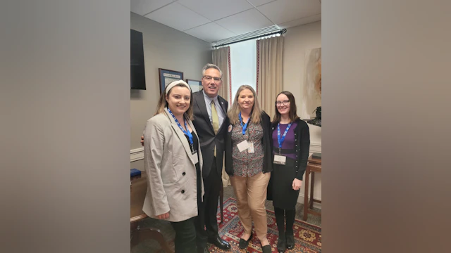 Three advocates pose with a state legislator.