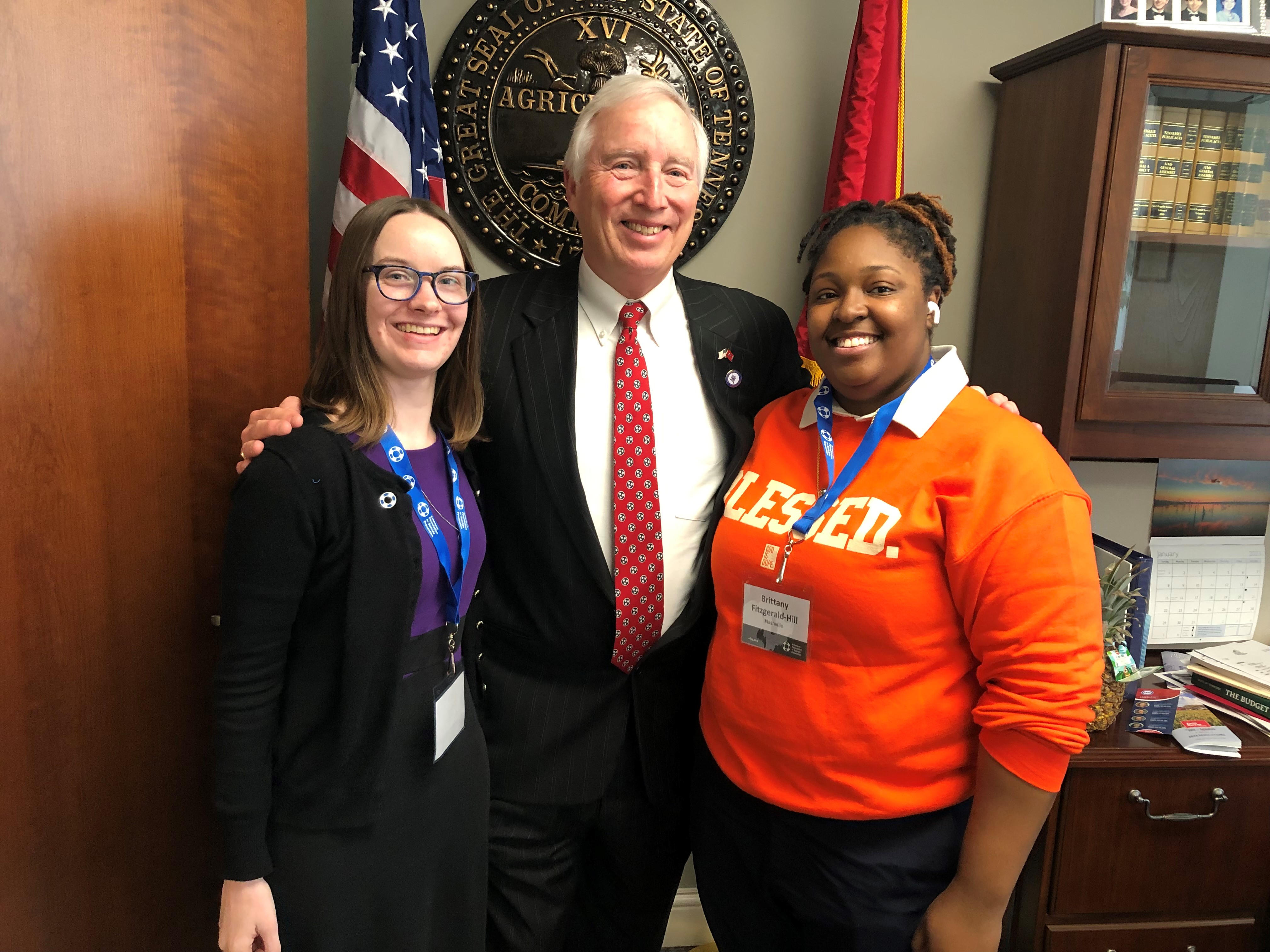 Two advocates pose with a state legislator.