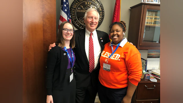 Two advocates pose with a state legislator.