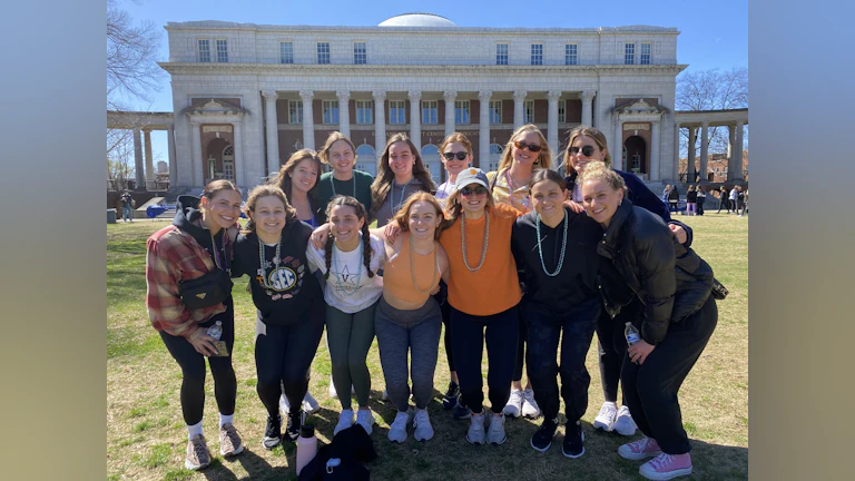 A group of college students pose in front of an acadmic building