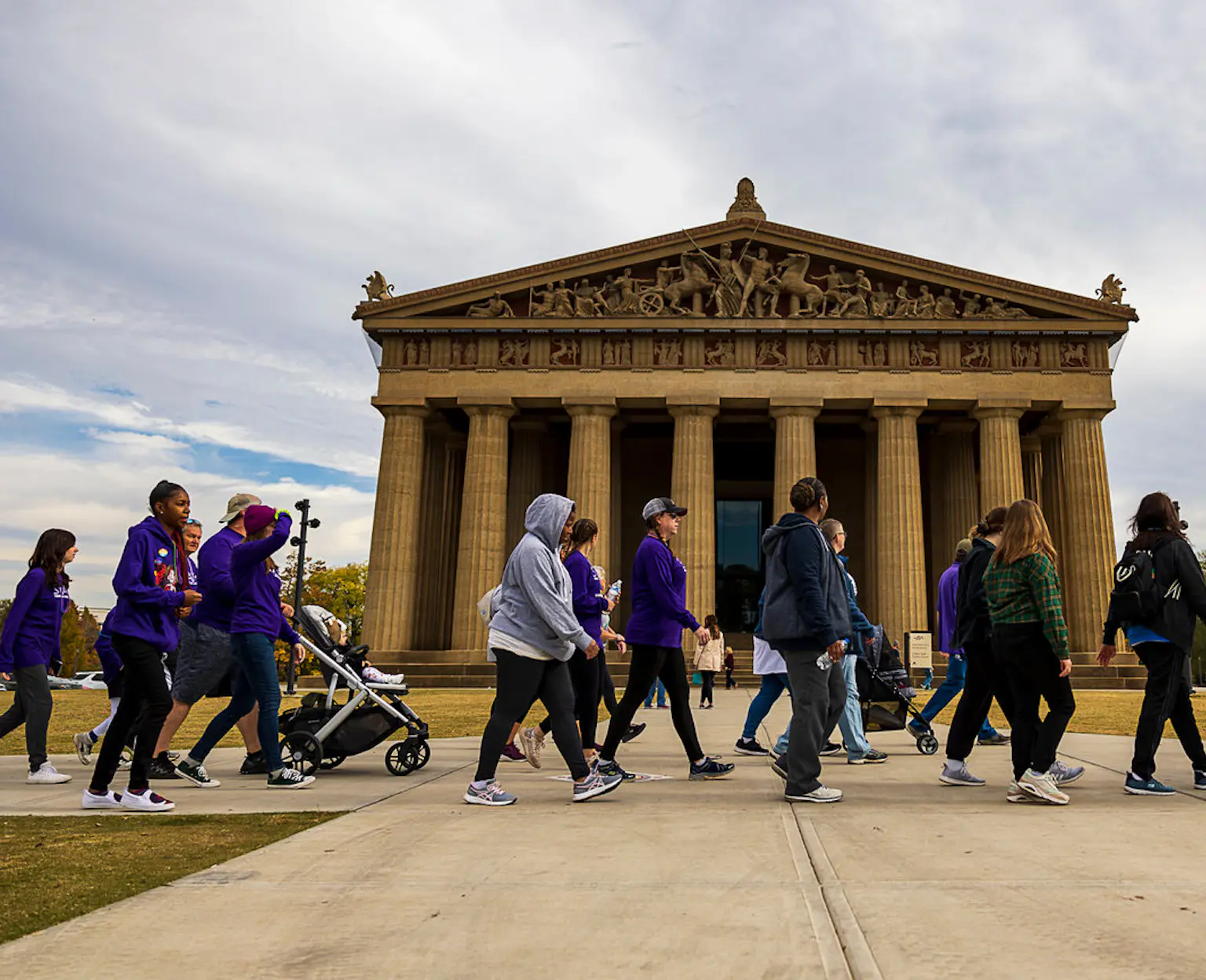 Walkers walk in front of the Parthenon