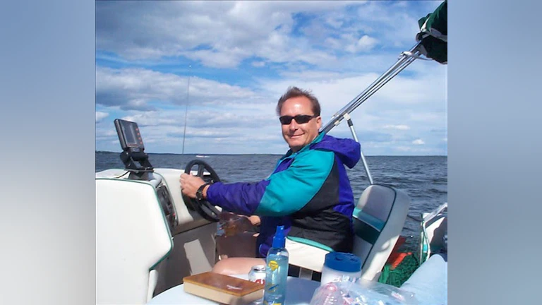 Jenniffer Moffett's stepdad Tom smiling and driving a boat.