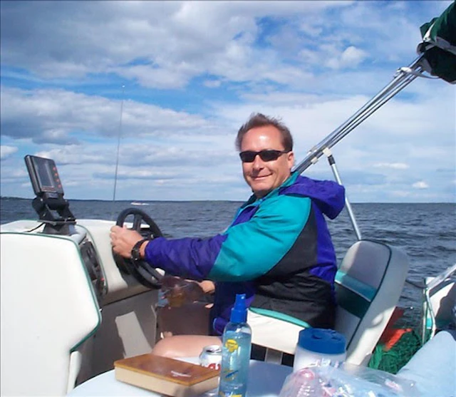 Jenniffer Moffett's stepdad Tom smiling and driving a boat.