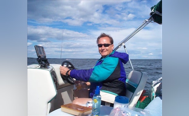Jenniffer Moffett's stepdad Tom smiling and driving a boat.
