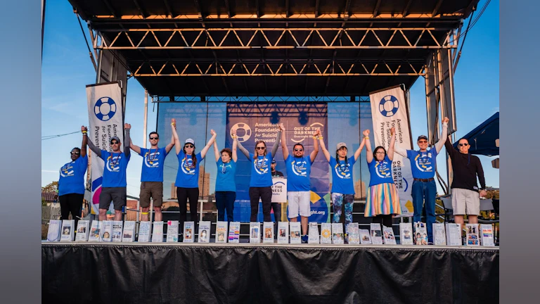 Hannah Moch standing on stage a with a group of people at an Out of the Darkness Overnight Walk.