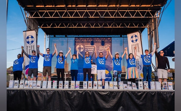 Hannah Moch standing on stage a with a group of people at an Out of the Darkness Overnight Walk.