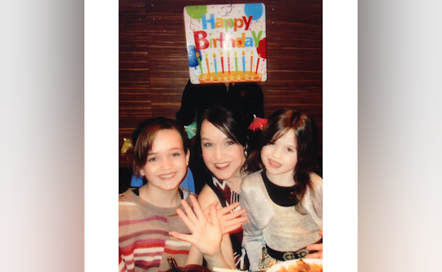 Young Taylor Ryan with her mother, Sabrina Jones, and a "Happy Birthday!" sign in the background.
