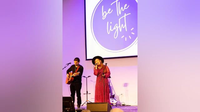 A woman is singing on stage and accompanied by a guitarist