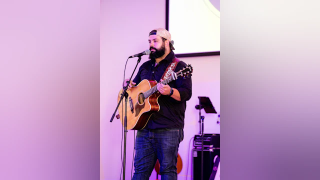 A man holds a guitar on stage