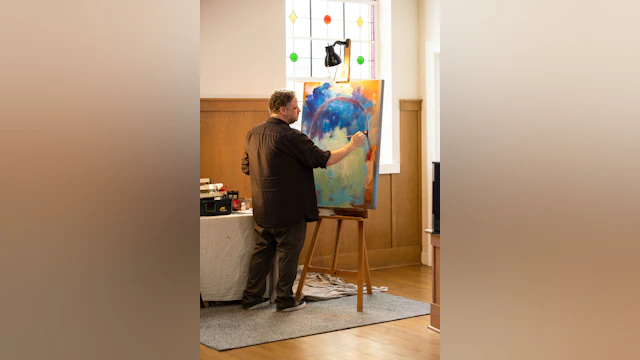 A visual artist works on a painting