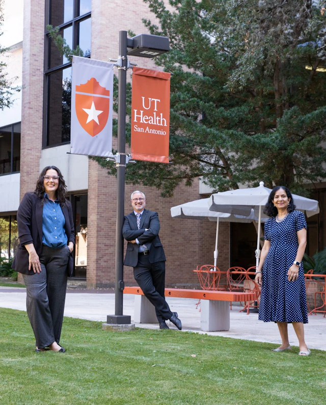 UT Health physicians stand outside on grass and smile at the camera