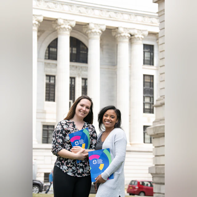 Two women holding AFSP folders in front of a government building