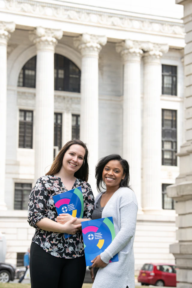 Two women holding AFSP folders in front of a government building