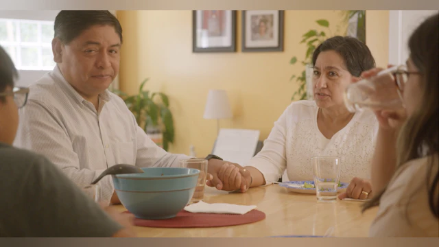 Family sitting around a dining table as the parents listen to their children