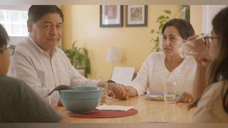 Family sitting around a dining table as the parents listen to their children