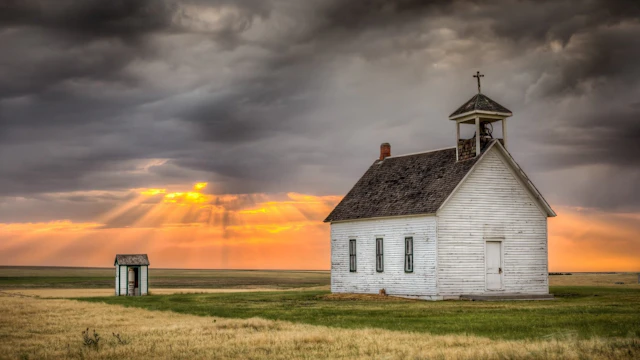 A church in a field at sunset.