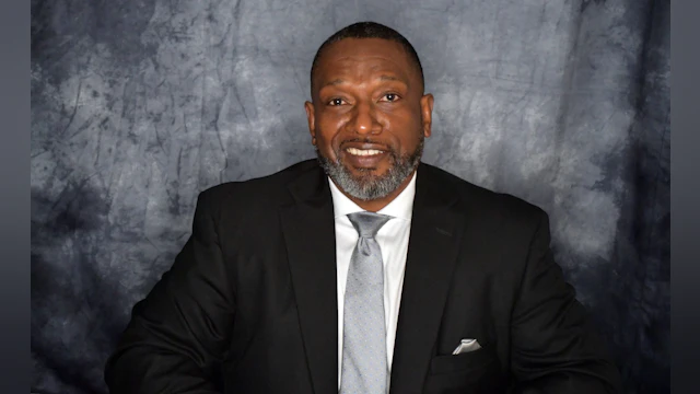 Photo of Victor Armstrong wearing a suit and smiling at the camera