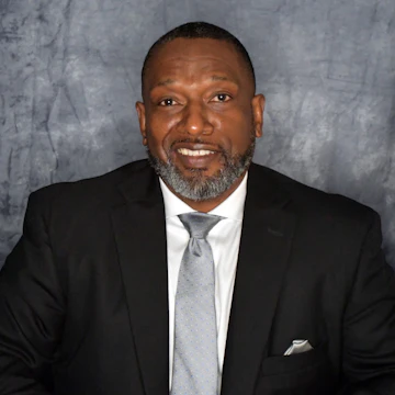 Photo of Victor Armstrong wearing a suit and smiling at the camera