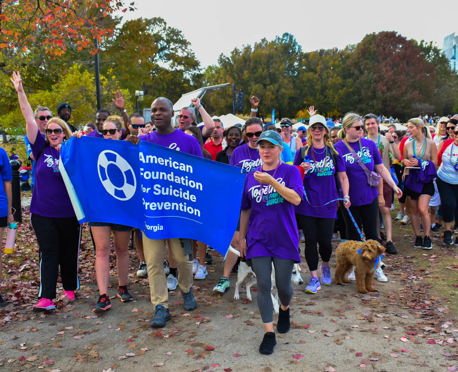 Crowd of people walking with a banner at community Out of the Darkness Suiicide Prevention event.