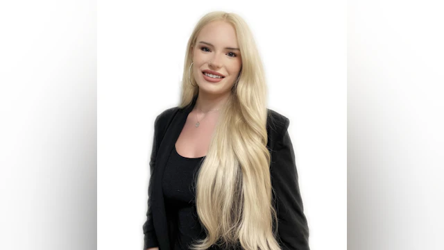 The author, Willow Danielle, smiling against a white backdrop. She is wearing a black top and black blazer.
