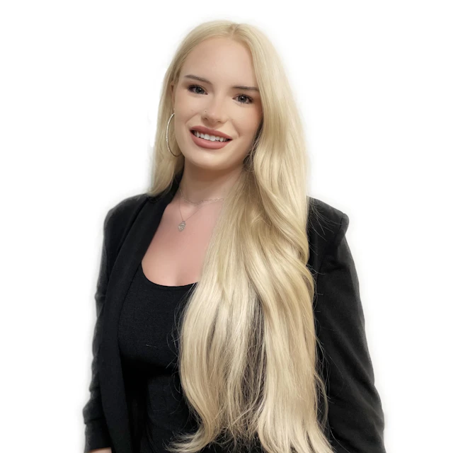 The author, Willow Danielle, smiling against a white backdrop. She is wearing a black top and black blazer.