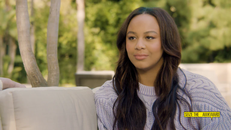 Nia Souix sits in front of a wooded outdoor area