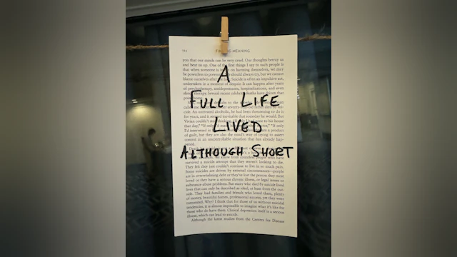 A message written in marker on a page from a book, clipped to a string with a clothespin