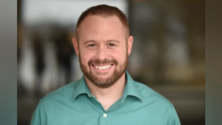 Headshot of the author, Ryan Price, MPA, AFSP Director of Chapter Engagement. Ryan is smiling and wearing a green top.