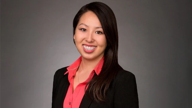 A headshot of the author, Darlene Tzou, smiling and wearing a salmon-pink shirt with a black blazer.
