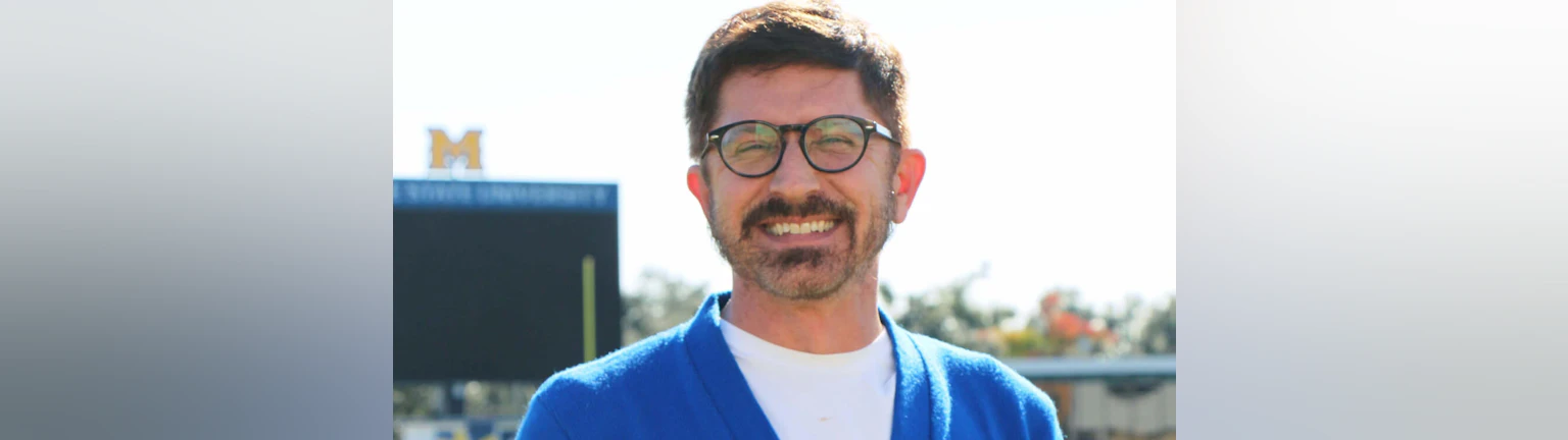 The author, Kevin Yaudes, smiling outdoors and wearing a blue sweater.