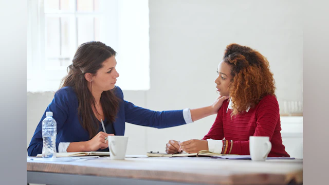Coworker comforts a colleague by placing a hand on their shoulder