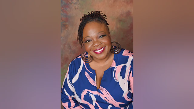 LaKeitha Phillips smiling for a headshot and wearing a blue top with a pink and white abstract design.