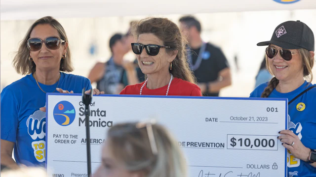 Bridget McCarthy smiling and holding a large donation check for AFSP.