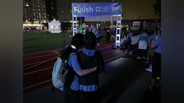 Marie and her child standing at The Overnight Walk finish line.