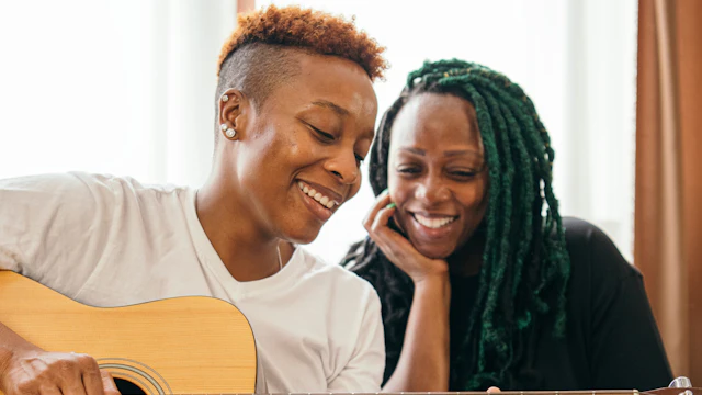 Two women together playing guitar