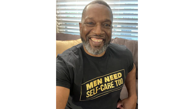 The author, Vic Armstrong, wearing a t-shirt that says "MEN NEED SELF-CARE TOO" in bright yellow block letters.