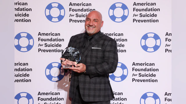 Media personality Jay Glazer holding his Public Service Lifesaver Award on the red carpet.