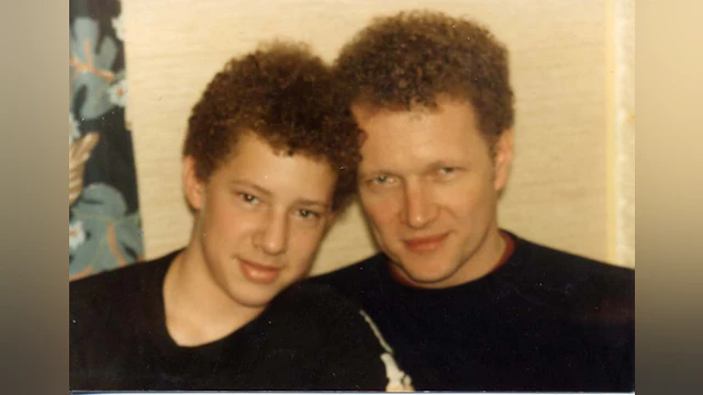 Dan smiling and sitting next to his father.