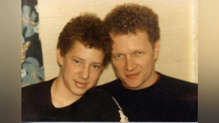 Dan smiling and sitting next to his father.