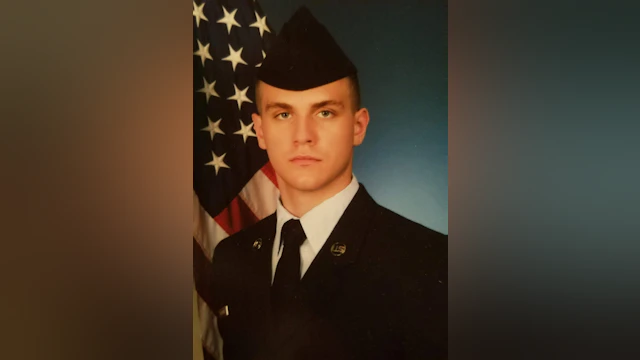 Karly Steinwehr's brother, Korbin Steinwehr, in uniform with an American flag in the background.