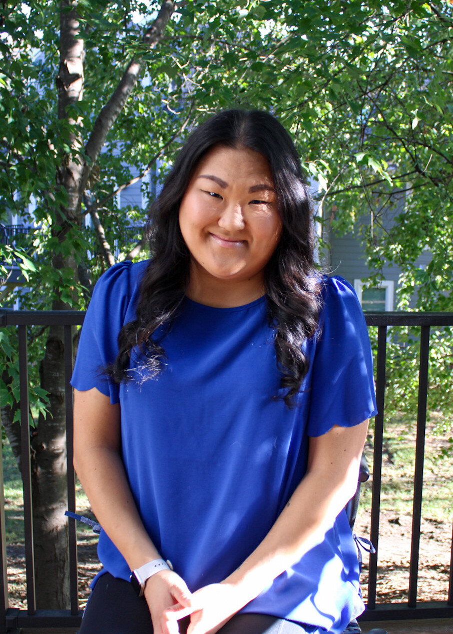 AFSP Iowa Chapter volunteer Eleanor Vestal smiling for a photo, wearing a bright blue top and sitting outdoors on a sunny day.