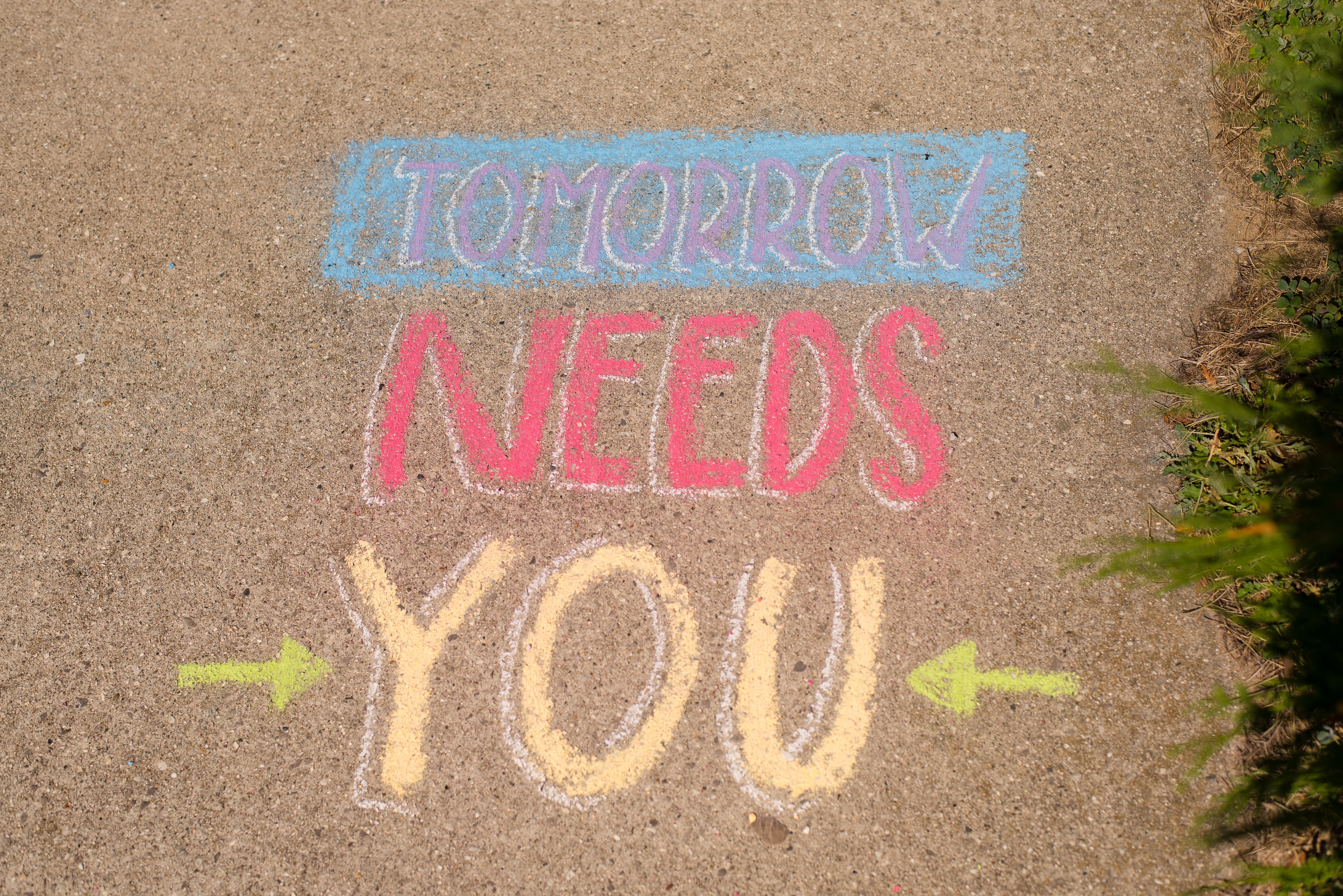 Sidewalk chalk reading Tomorrow Needs You